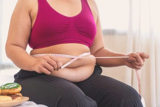 A woman measuring her waist with a tape measure