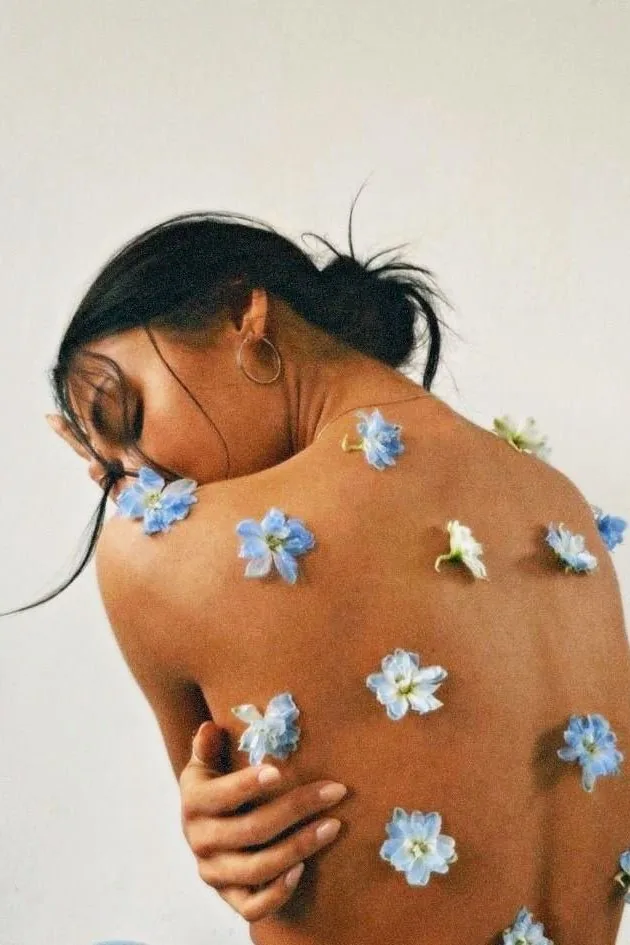 A woman's back scattered with small blue flowers