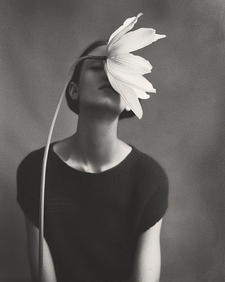 A woman tilting her head back, a large flower resting against her face