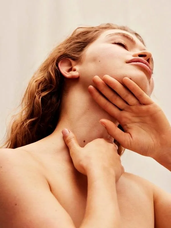 A woman touching her neck, eyes closed