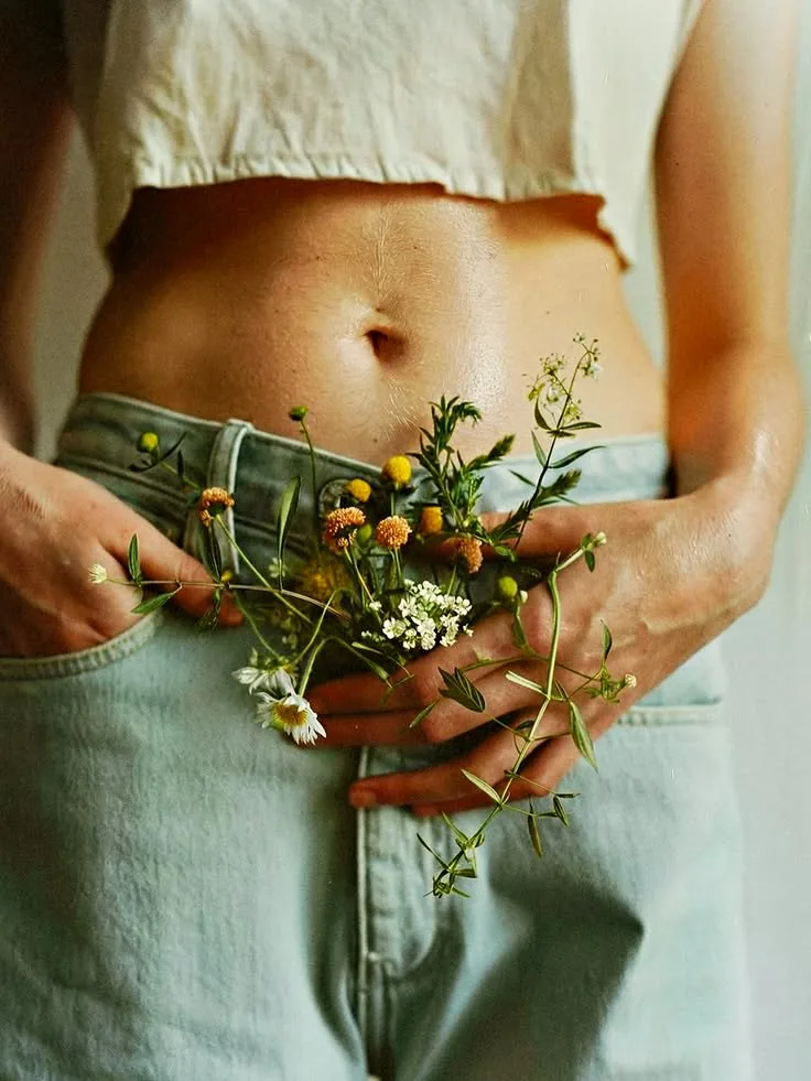A woman holding a bunch of wildflowers against her stomach
