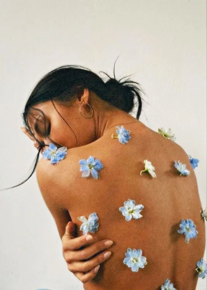 A woman's back scattered with small blue flowers