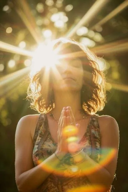 A woman meditating with hands at her heart, backlit by the sun