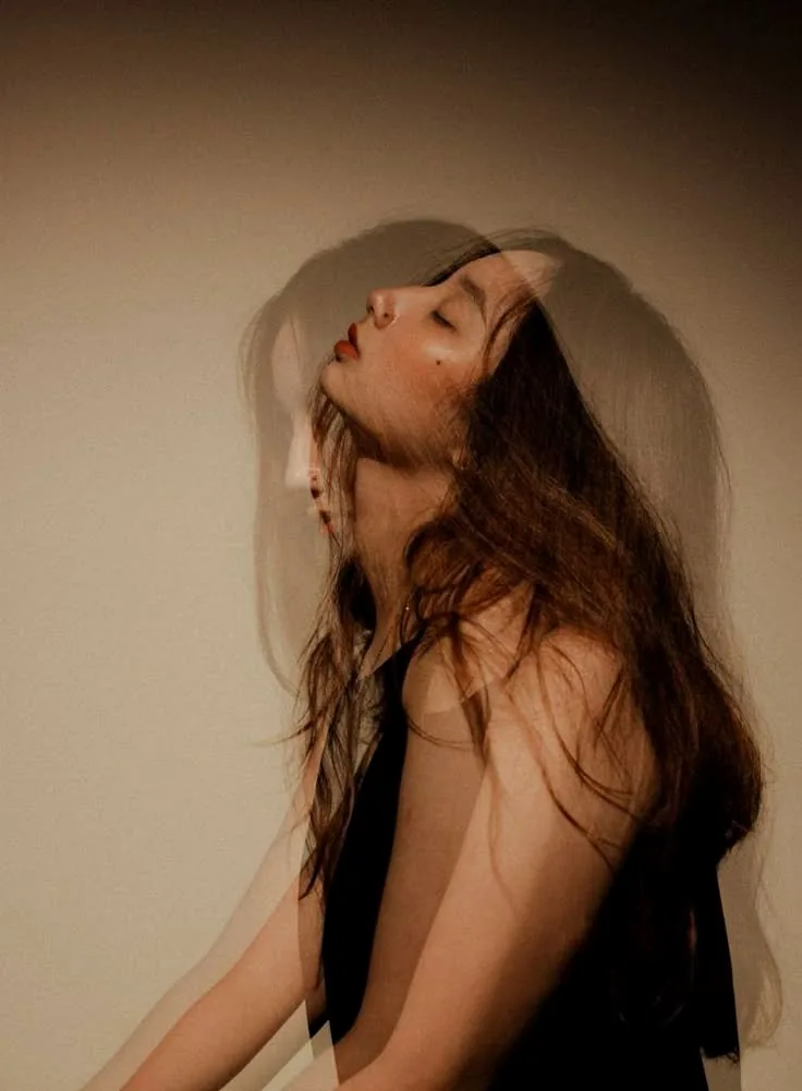 A woman with long hair resting her head back, eyes closed