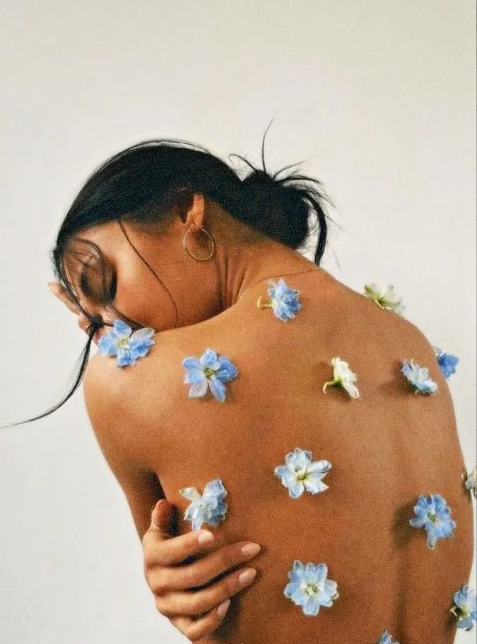 A woman's shoulders and back scattered with small blue flowers